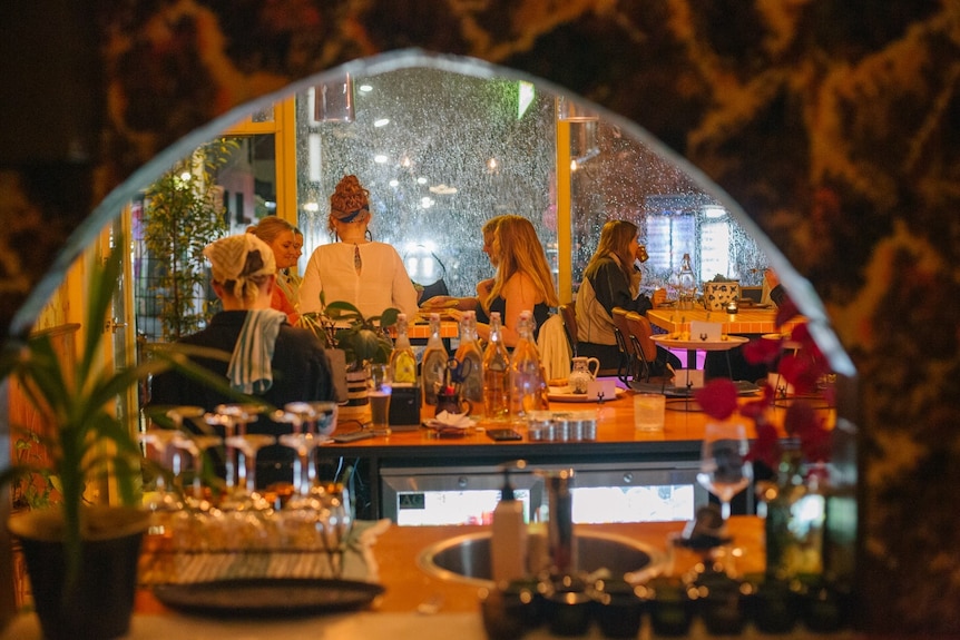 A picture of a restaurant taken in the reflection of a curved mirror behind a bar