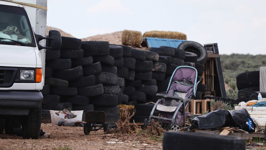 Debris including a baby stroller are seen outside the location where people camped.