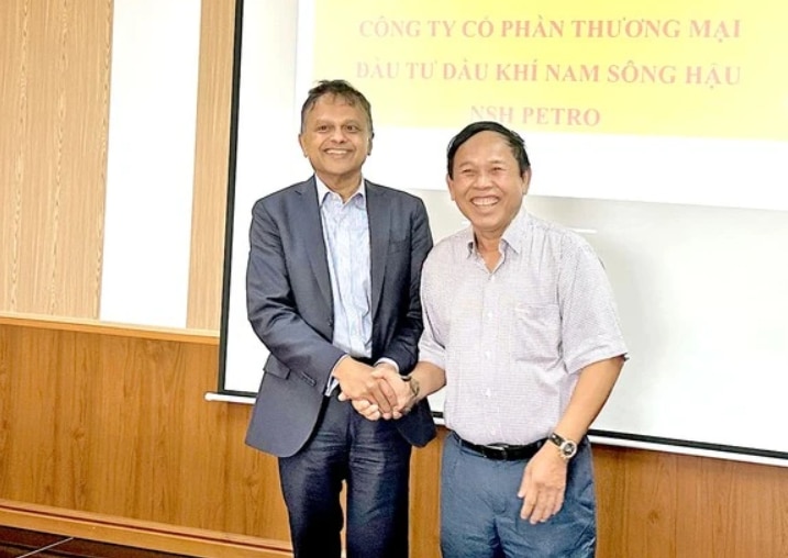 Two smiling men shake hands. 