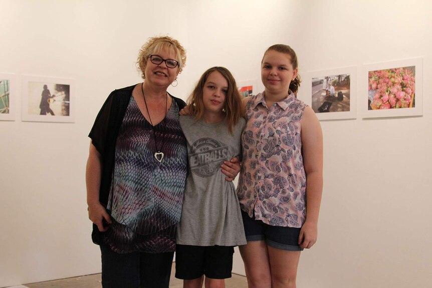 a family in front of photographs in a gallery