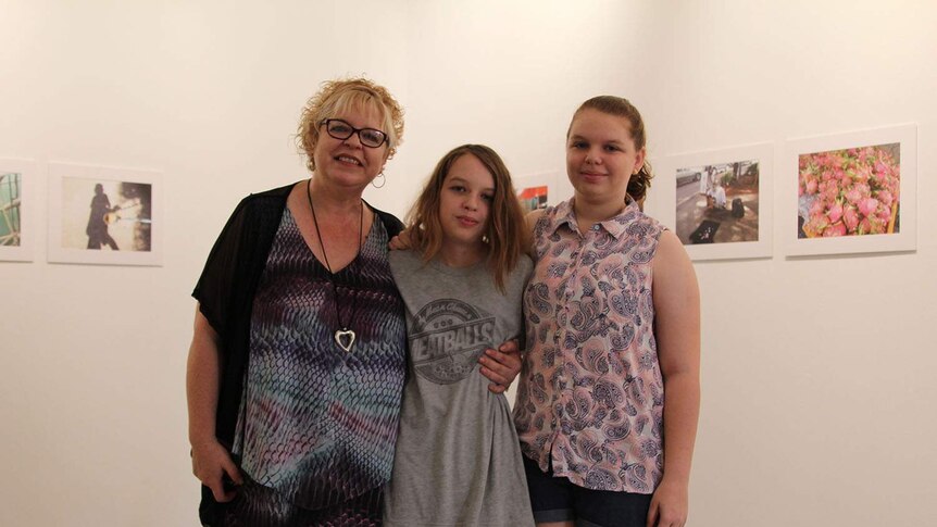 a family in front of photographs in a gallery