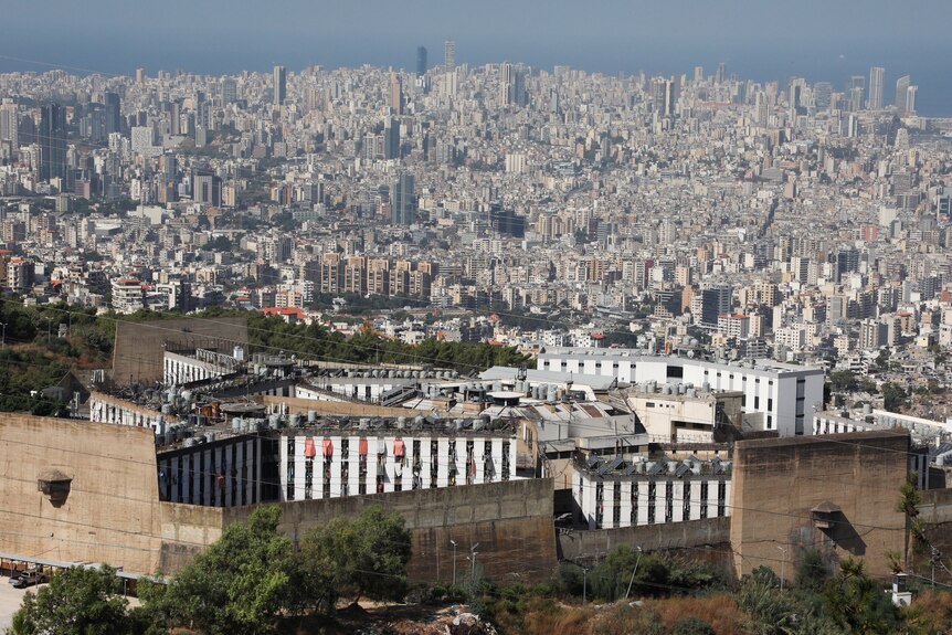 Several bland prison buildings are picture in the foreground, with the sprawl of Beirut in the background.