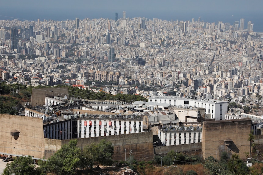 Several bland prison buildings are picture in the foreground, with the sprawl of Beirut in the background.