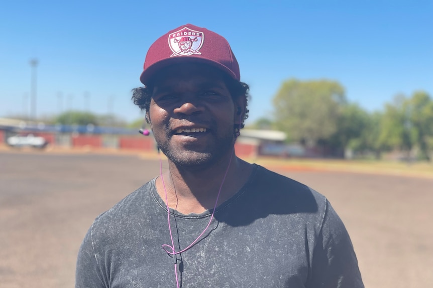 Indigenous man in red hat smiles to camera.