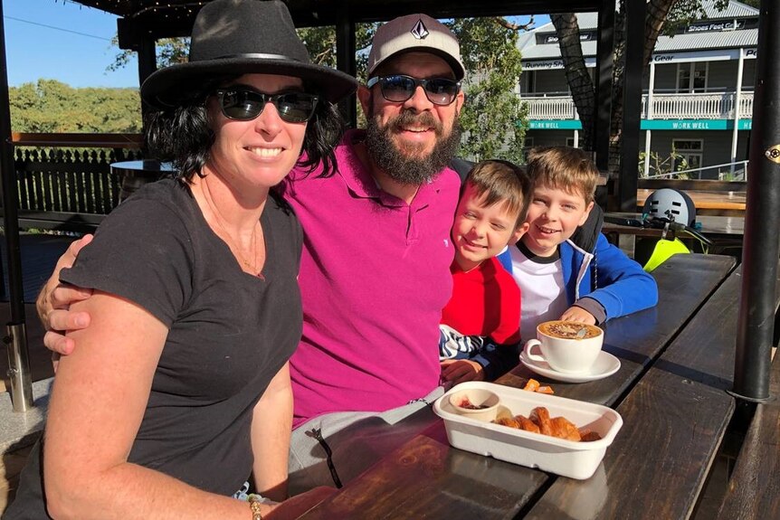 A woman sits with a man and two boys at a cafe table