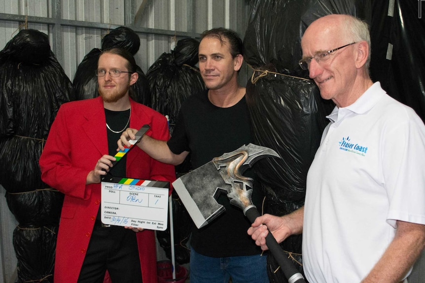 filmmaker Nick Aiton, director Chris Sun and Fraser Coast mayor Chris Loft post with movie props