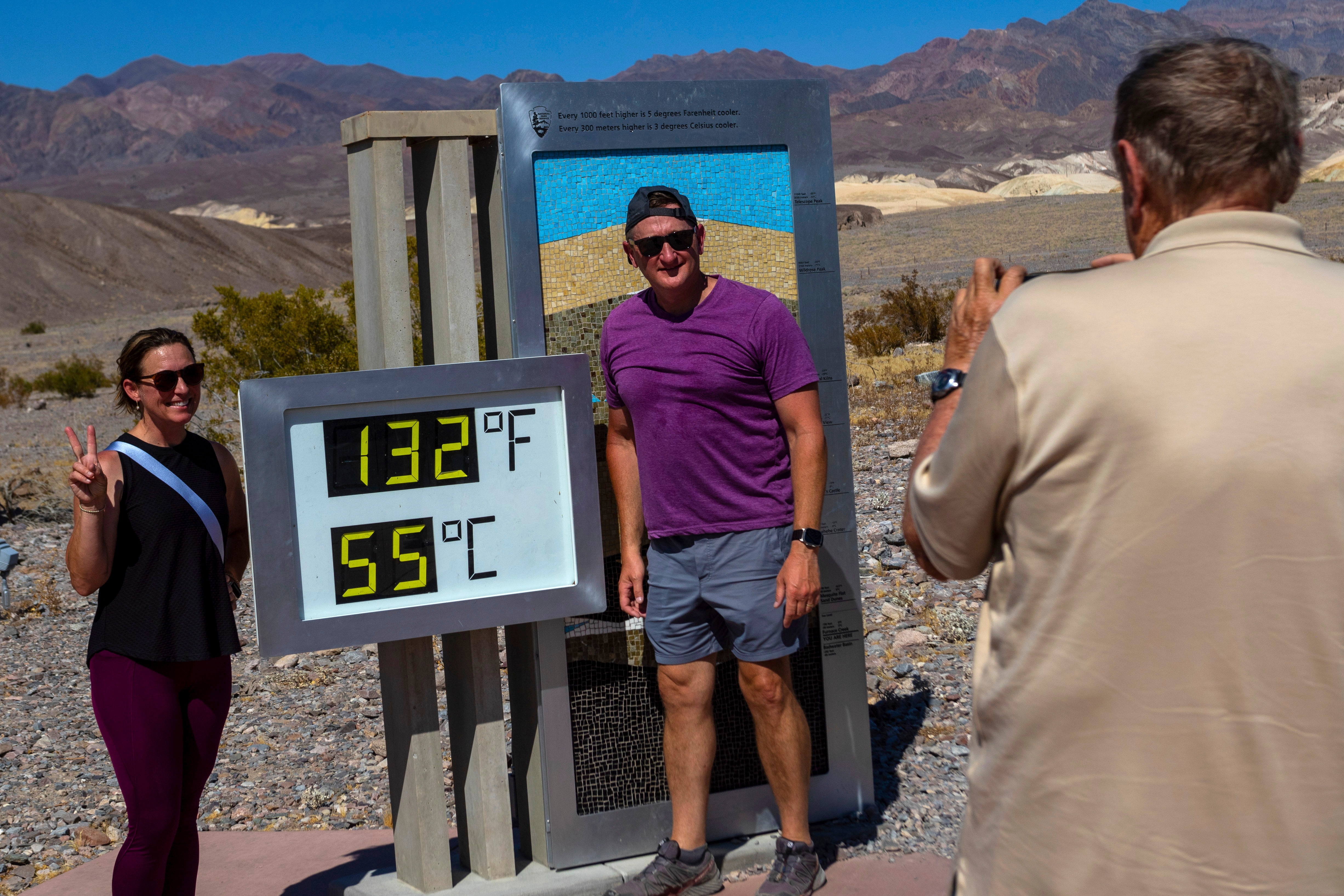 Two people pose for a picture beside a sign reading "132F" and "55F".