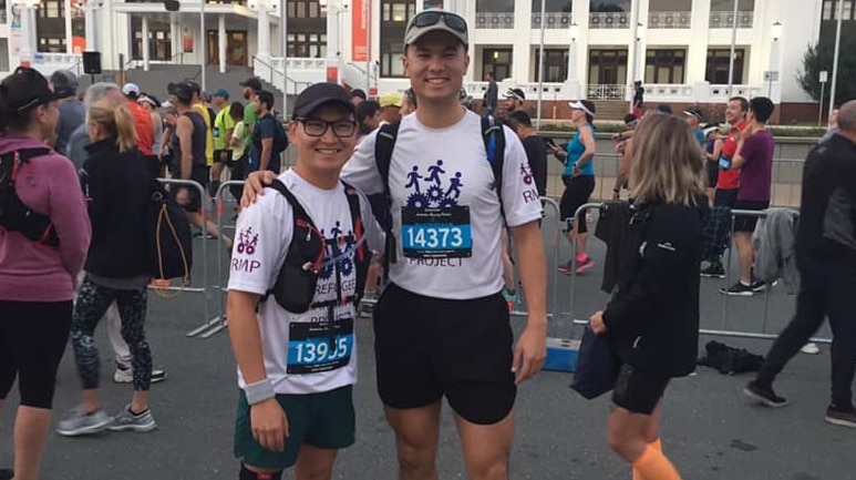 Zaki Haidari poses in running gear with another man outside Old Parliament House in Canberra.