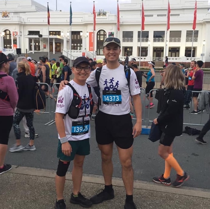 Zaki Haidari poses in running gear with another man outside Old Parliament House in Canberra.