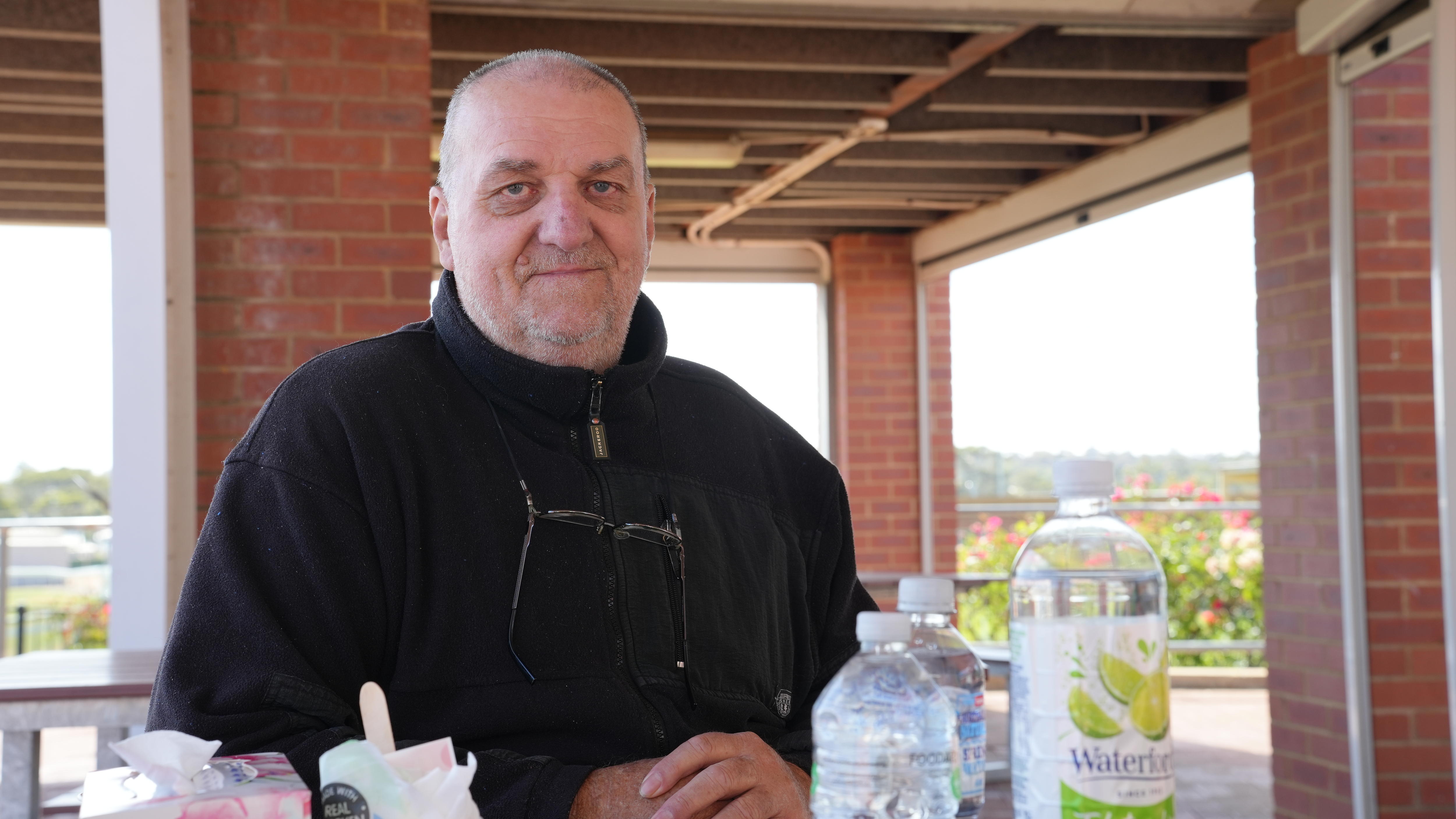 Un hombre sentado en una mesa con botellas de agua frente a él.