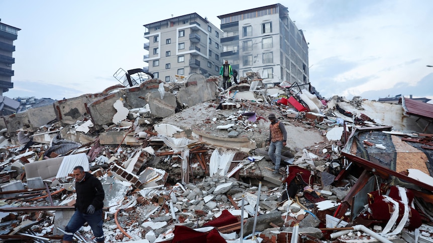 People walk amid rubble following an earthquake in Hatay, Turkey