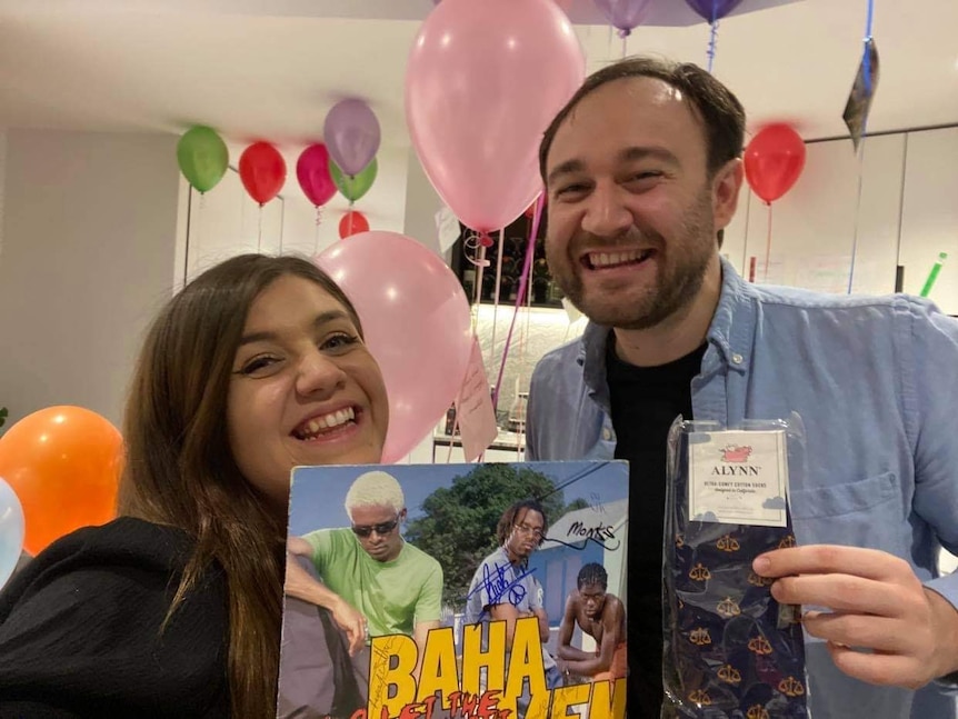 A woman and a man, smiling, with a signed record of the Baha Men.