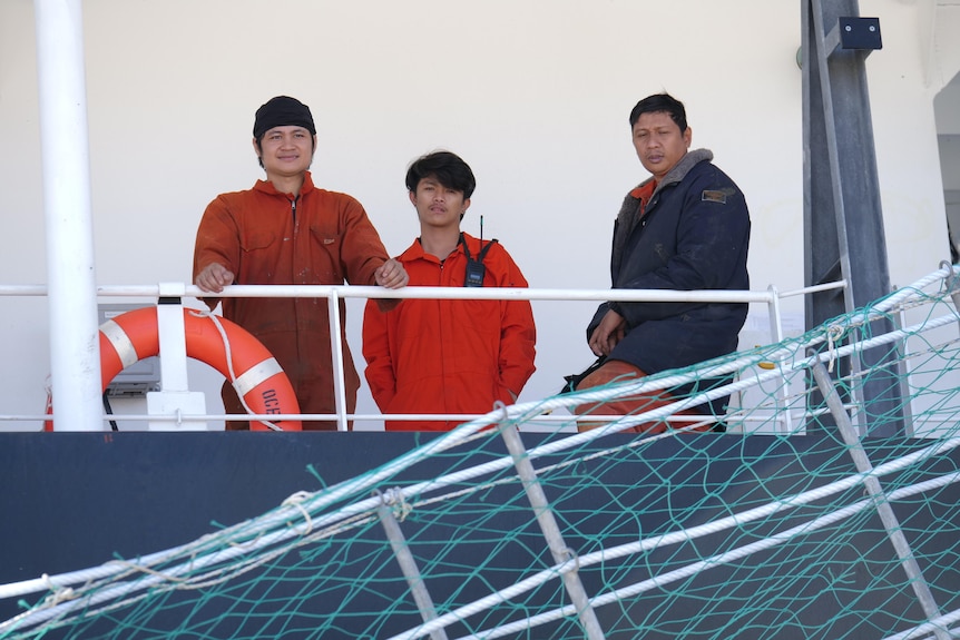 three seamen high up on a deck of a large vessel
