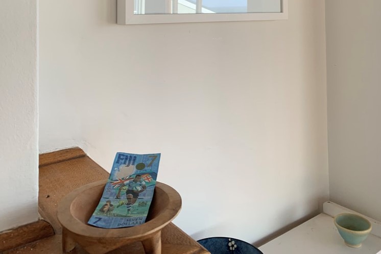 Wooden bowl with blue note, behind it on the wall a painting.