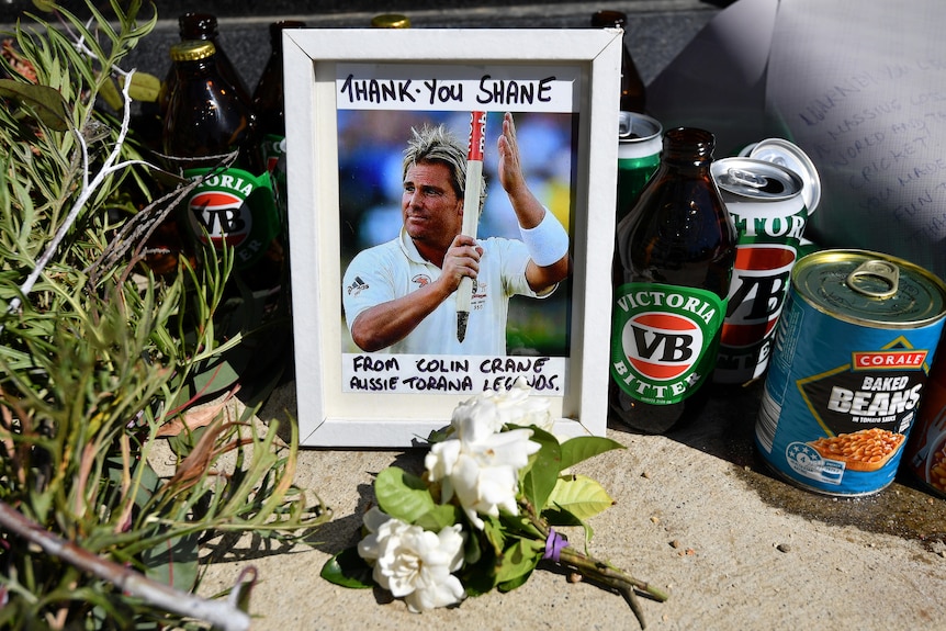 A framed photograph of Shane Warne on the cricket pitch says 'THANK YOU SHANE'.