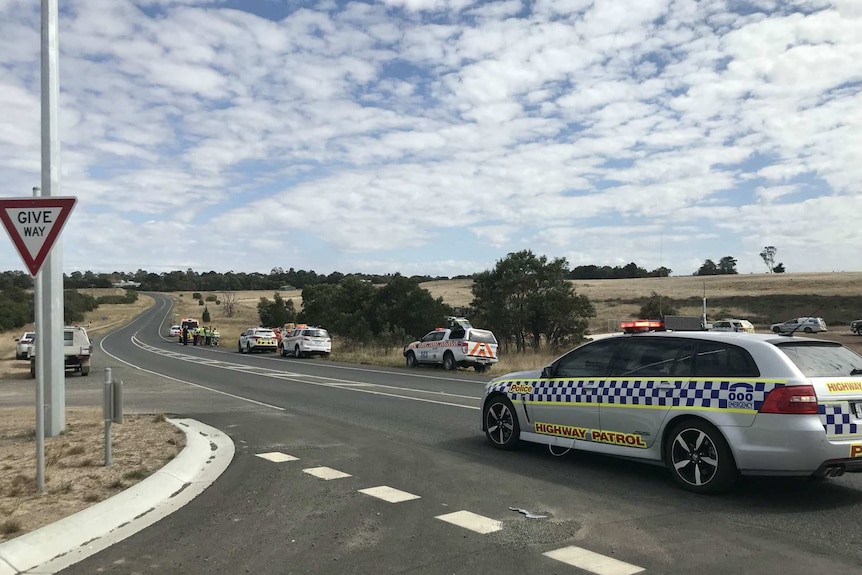 Police and emergency services vehicles line the Glenelg highway near the collapsed trench.