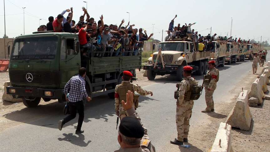 Iraqi volunteers for fight against insurgents stand on back of trucks