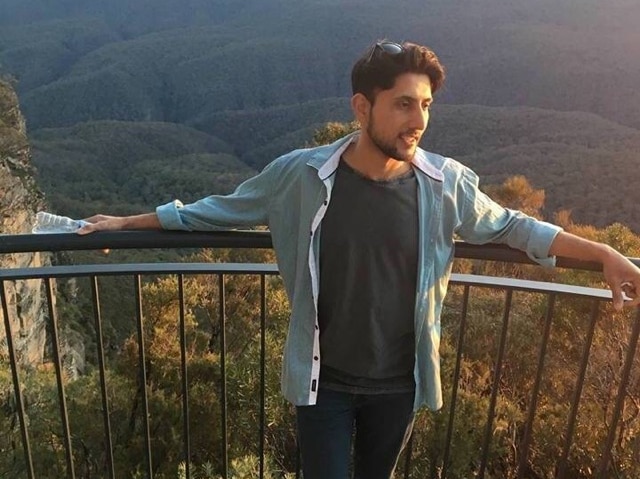 Zeeshan Akbar standing at a lookout near mountain ranges.