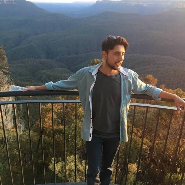 Zeeshan Akbar standing at a lookout near mountain ranges.