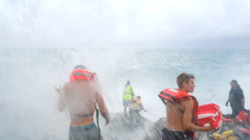 Locals are buffeted by spray from rough surf