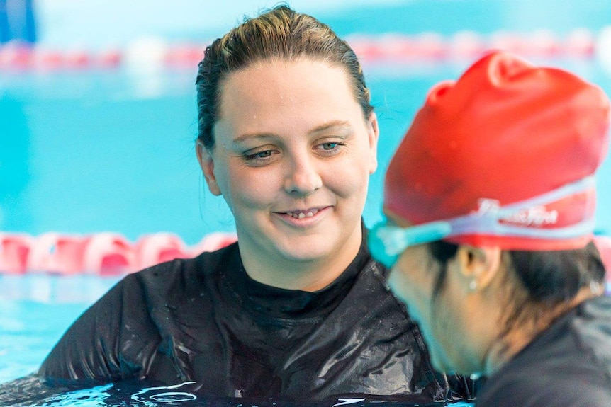 Swimming coach watches of student in the pool.