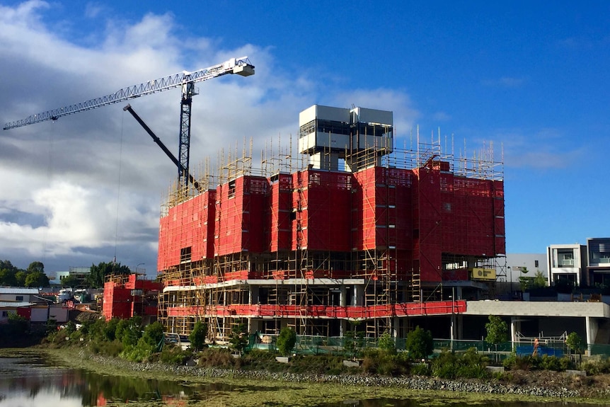 Wide shot of an unfinished building with scaffolding and crane.