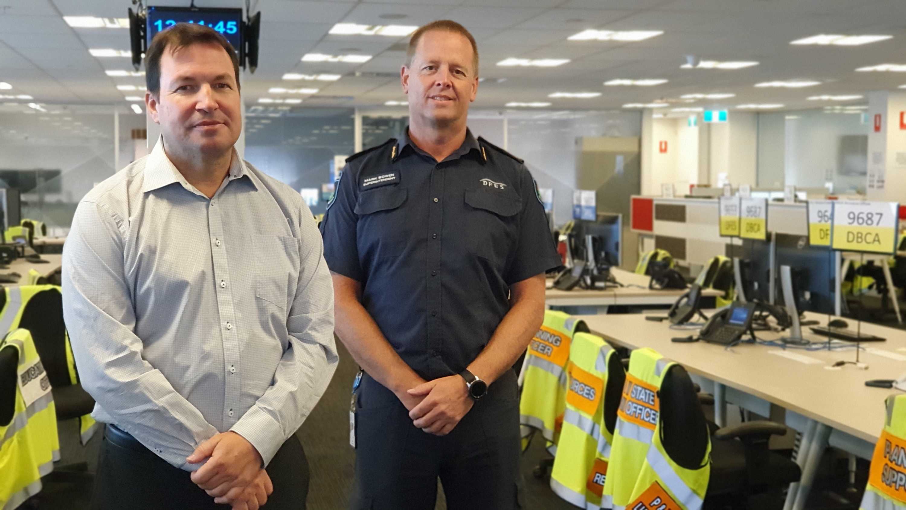 Two men from DFES stand in building between desks