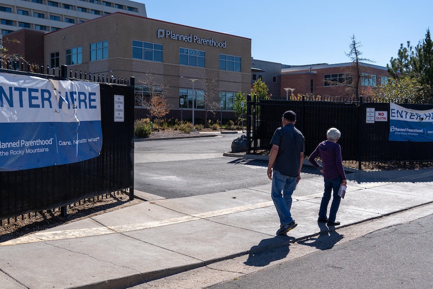 Two elderly people standing outside the entrance to a Planned Parenthood clinic.