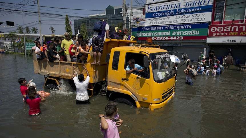 Local residents leave their homes carrying with them what they can after a mud and sandbag wall collapsed in suburban Bangkok.