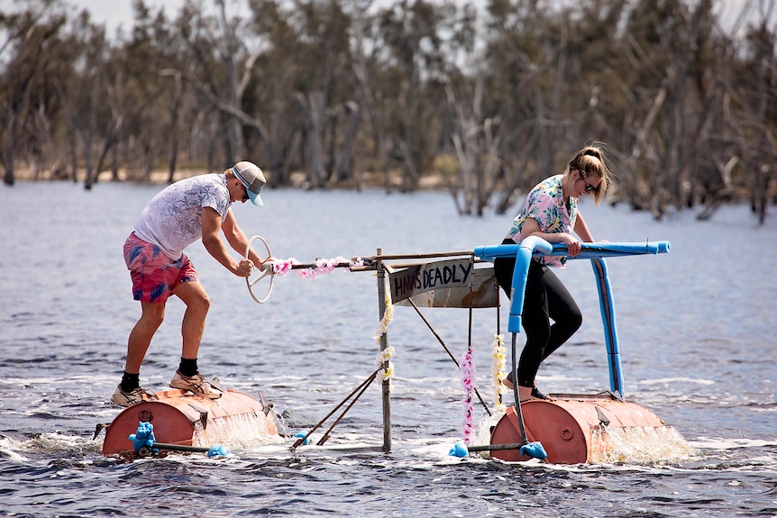 two people on a homemade boat made of old 44 gallon drums