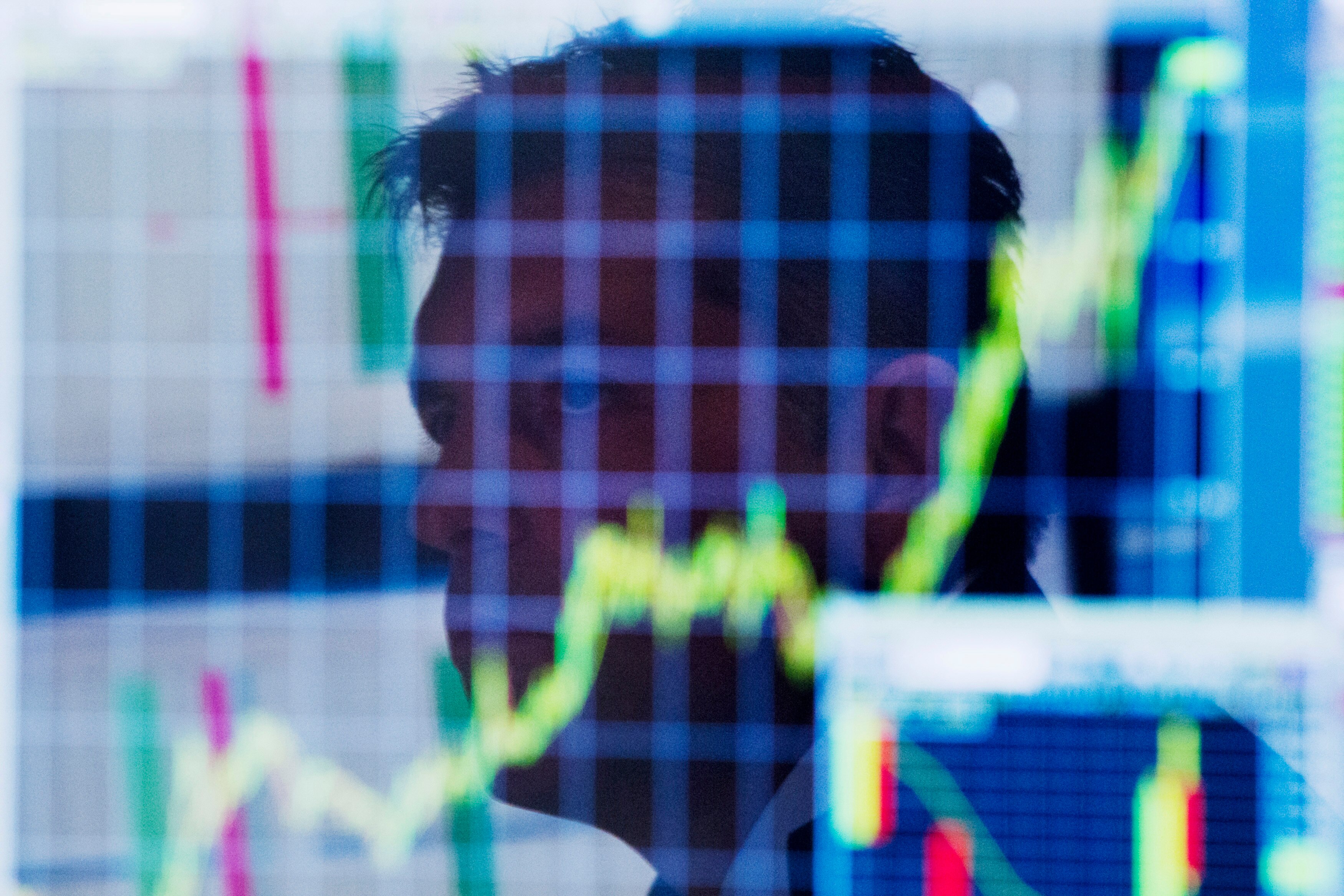 A trader looks up at a chart on his computer screen while working on the floor of the New York Stock Exchange.