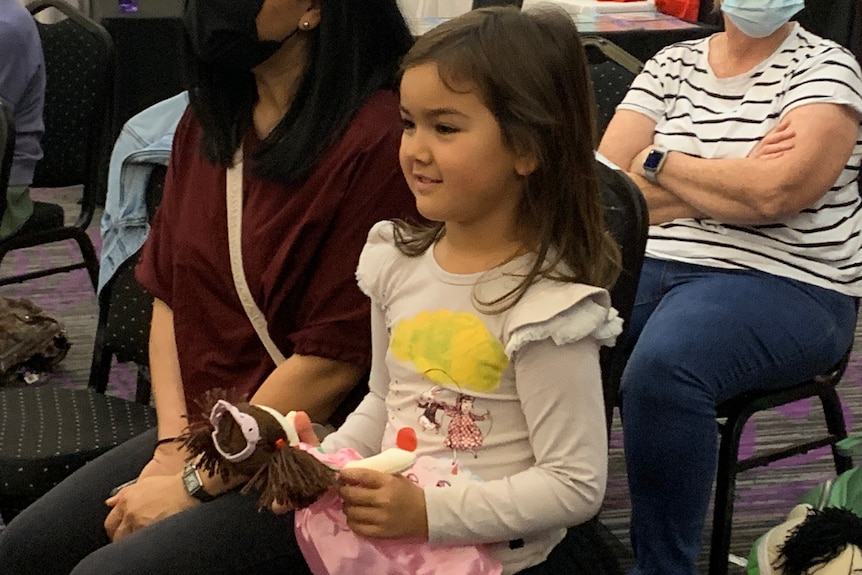 5 year old Leila Ryan smiling and sitting in the audience of the Playschool show clutching her Jemima doll  