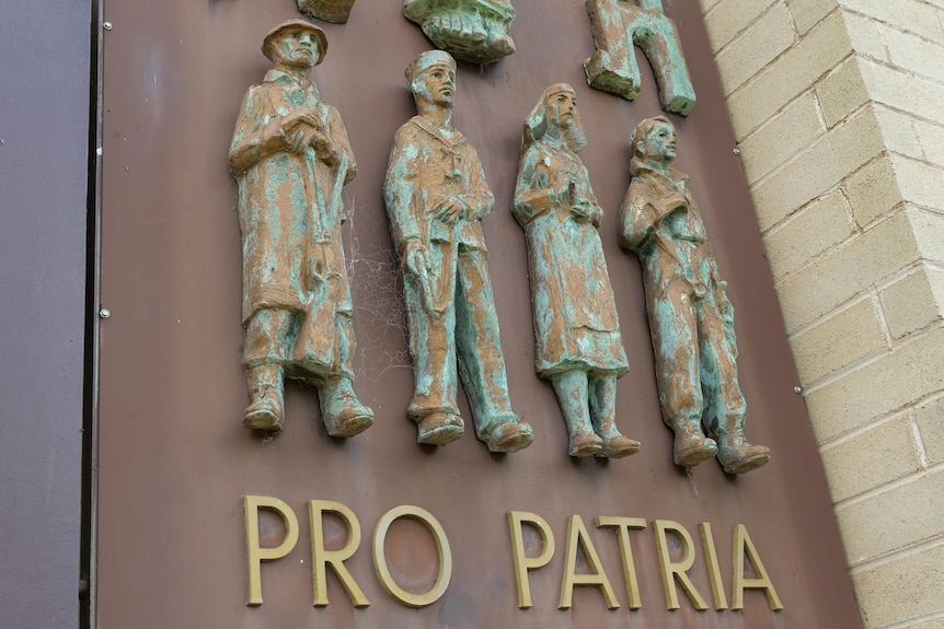 A sign with small statues of people and words underneath reading 'PRO PATRIA'