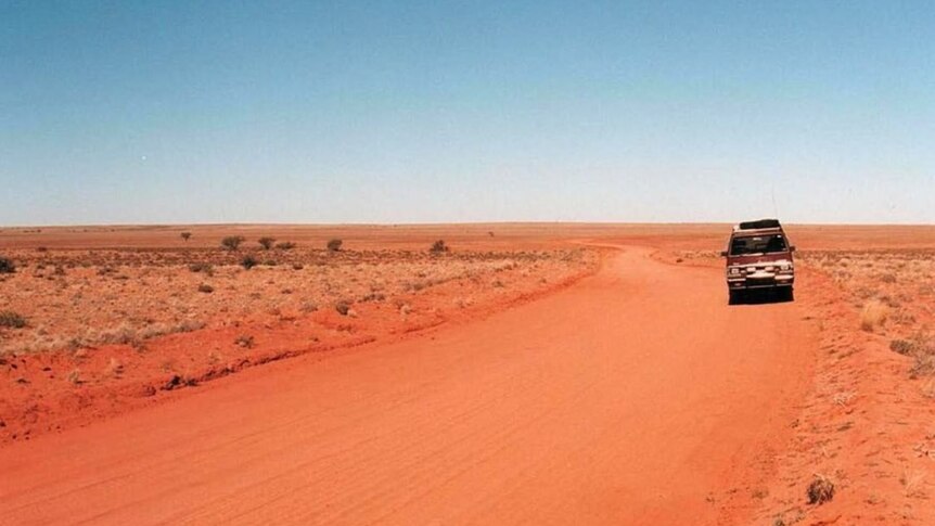 A four wheel drive on a red dirt track in the outback.