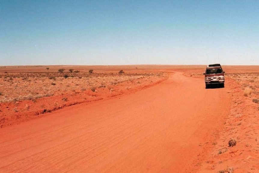 A four wheel drive on a red dirt track in the outback.