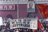 Chinese students carry a sign that reads "Give me democracy or give me death" during a large protest in Tiananment Square.