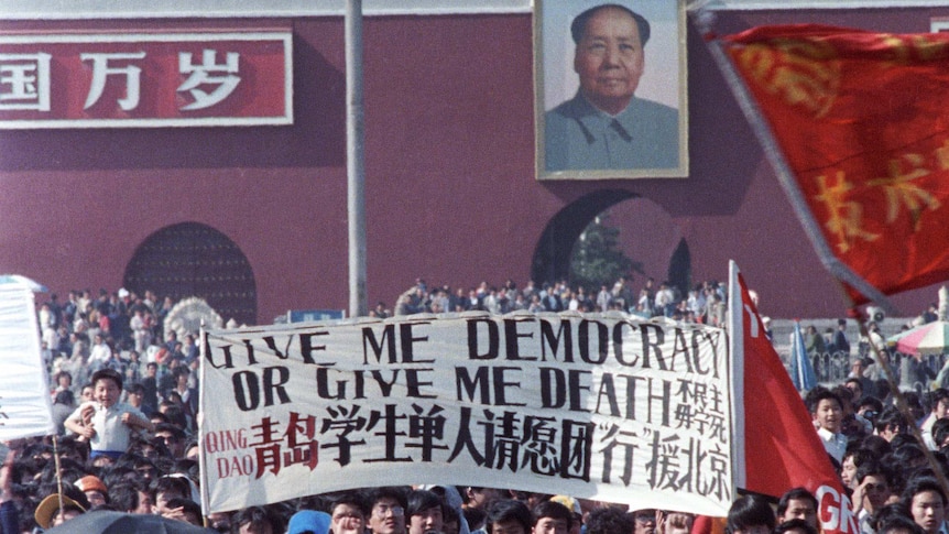 Chinese students carry a sign that reads "Give me democracy or give me death" during a large protest in Tiananment Square.