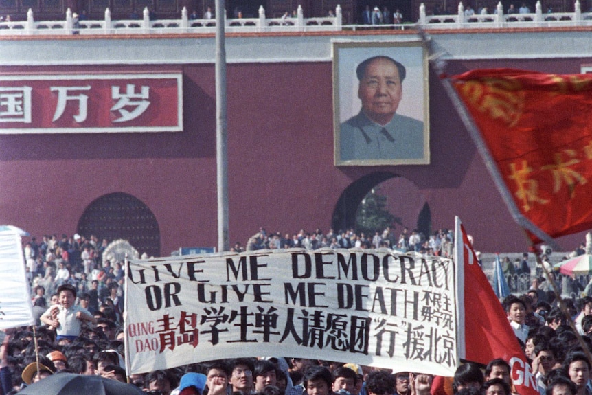 Chinese students carry a sign that reads "Give me democracy or give me death" during a large protest in Tiananment Square.