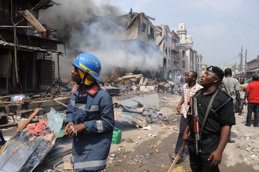 A policeman and firefighter look at the scene of a fire at a building stocked with fireworks in Lagos.