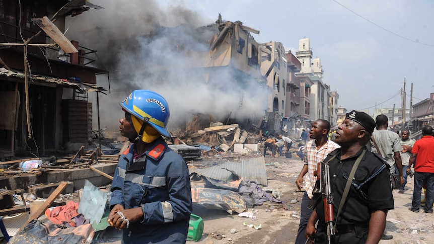 A policeman and firefighter look at the scene of a fire at a building stocked with fireworks in Lagos.