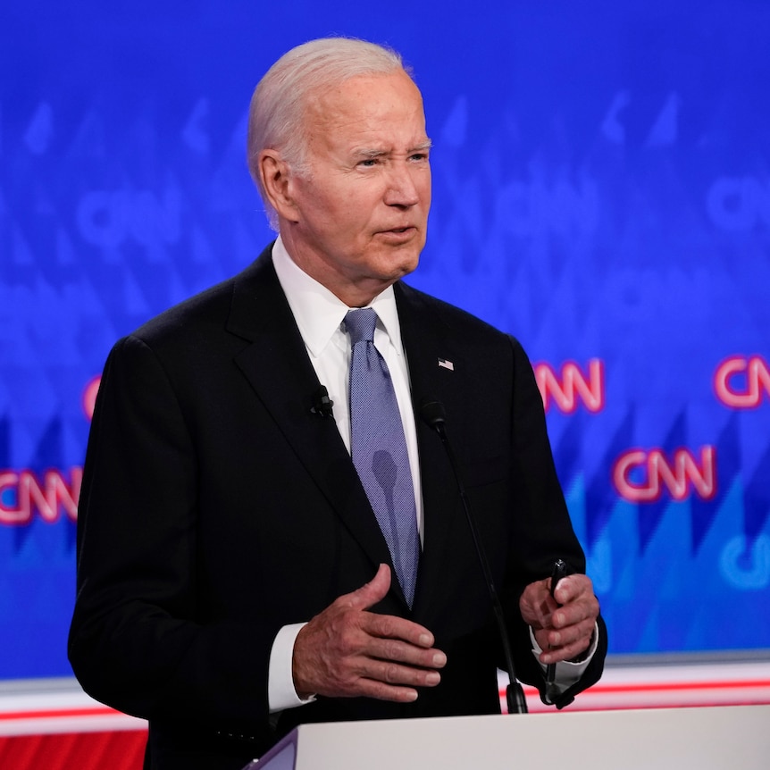 Joe Biden gestures with both hands as he speaks from behind a lectern during a studio debate.