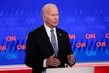 Joe Biden gestures with both hands as he speaks from behind a lectern during a studio debate.