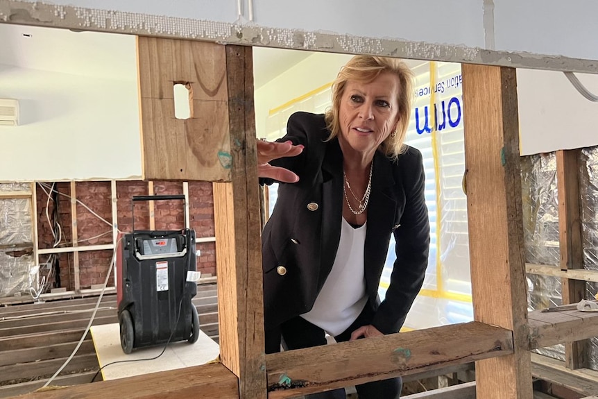 Middle aged woman looking through her flood-ruined home