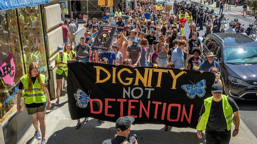 Crowds gather with signs saying Dignity Not Detention, march to fight for immigration justice