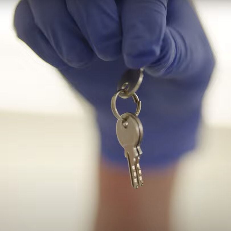 close up of human hand in blue rubber dangling a set of keys
