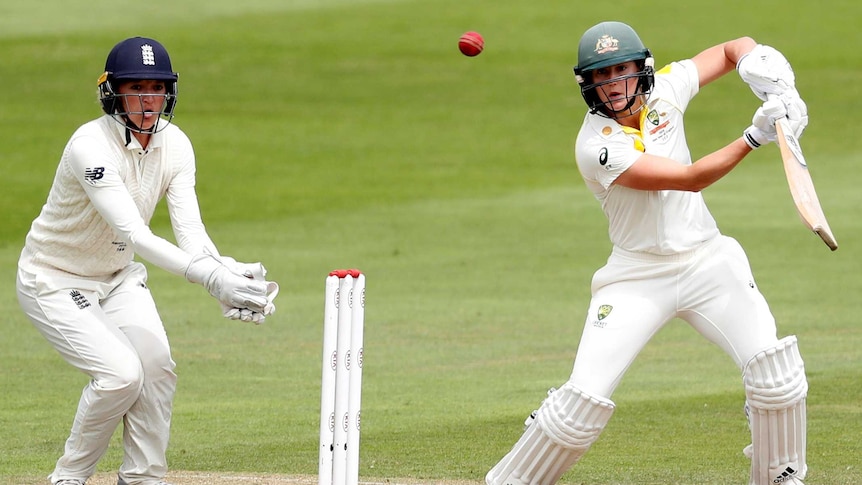 Australia batter Ellyse Perry and England wicketkeeper Sarah Taylor look at the cricket ball after Perry cuts during a Test.