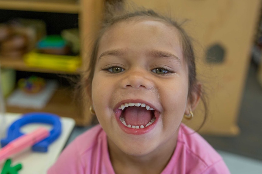 A girl grins broadly as she plays up for the camera.