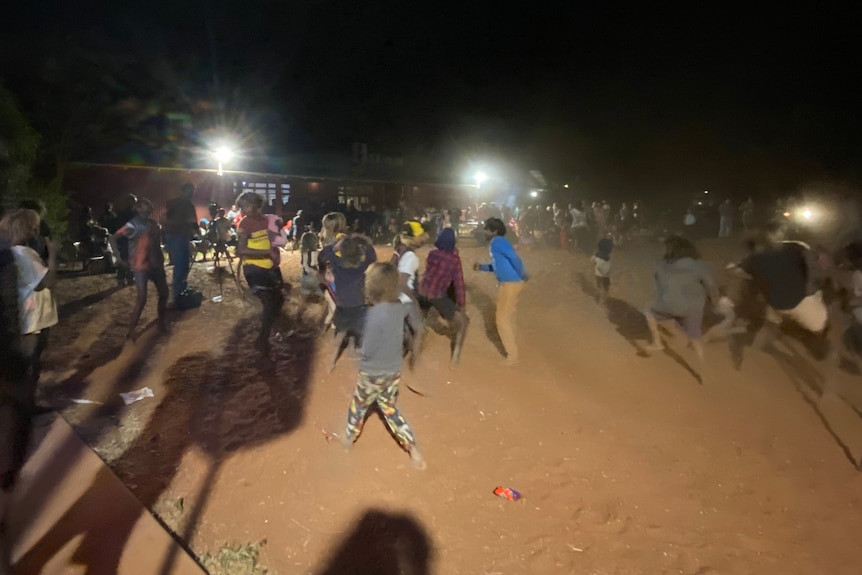 Kids dance in the dirt at an outback concert