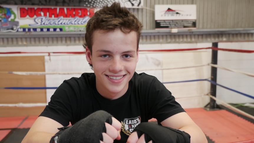 Close up photo of smiling white teenage male in a boxing ring