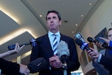 WA Education Minister Peter Collier in front of media microphones